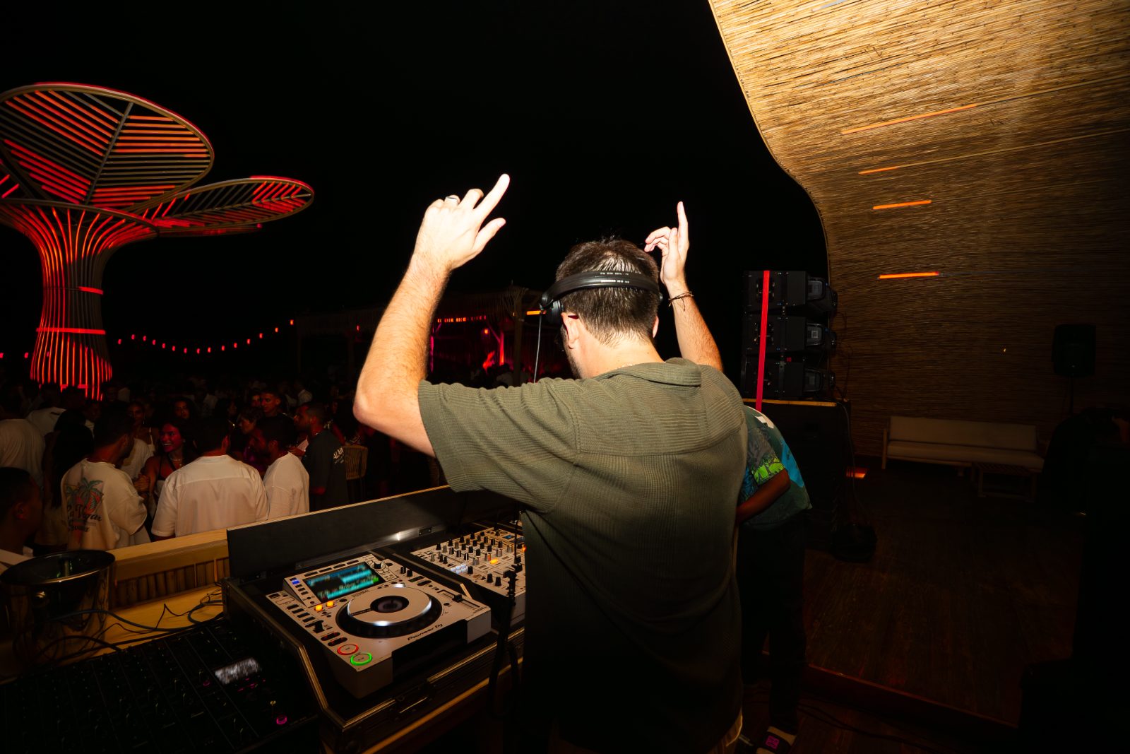 DJ performing under a red flower-petal canopy at a Casa Très summer party